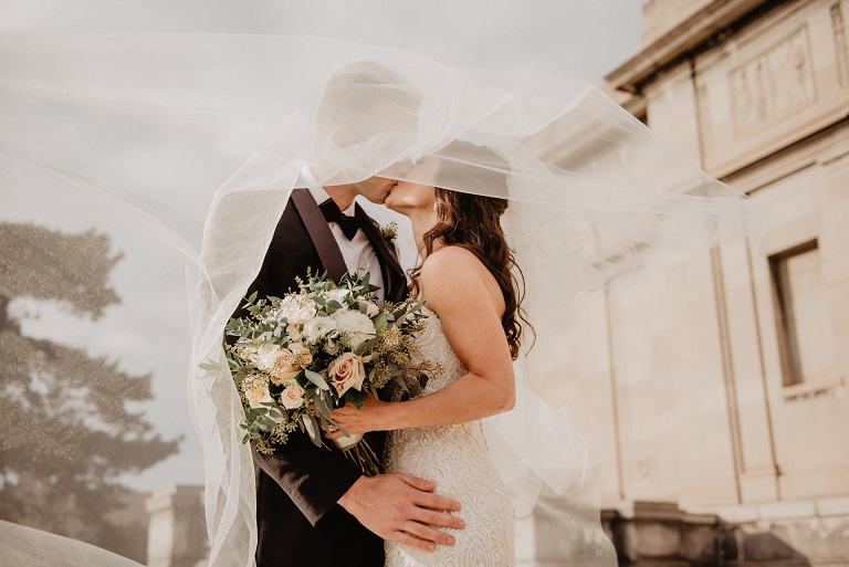 Bridge and groom kissing with bride holding bouquet