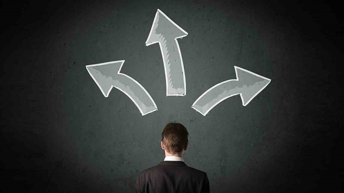 Man standing in front of three direction arrows