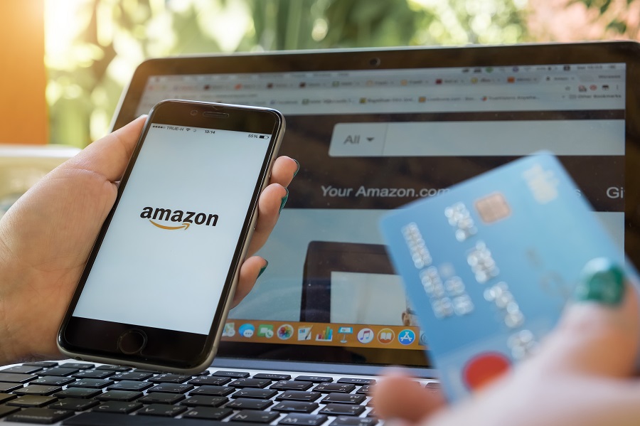 Woman holding phone with Amazon logo on left hand and a credit card on her right hand