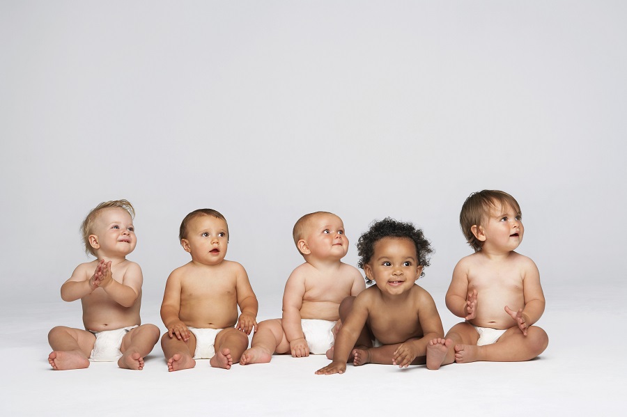 Row of five multiethnic babies against a white background