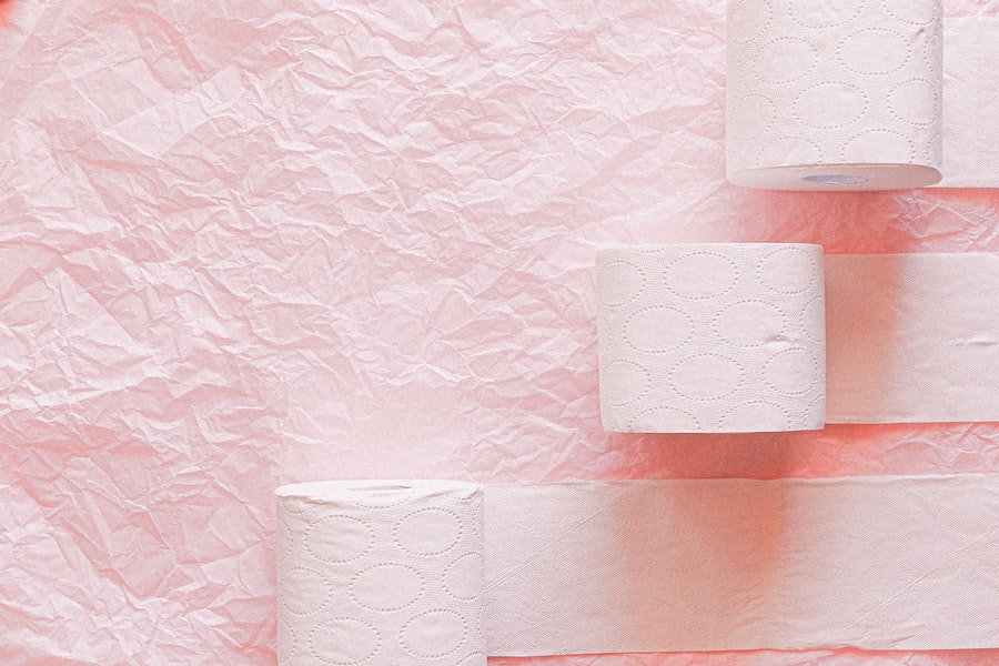 White toilet paper rolls on pink textile background