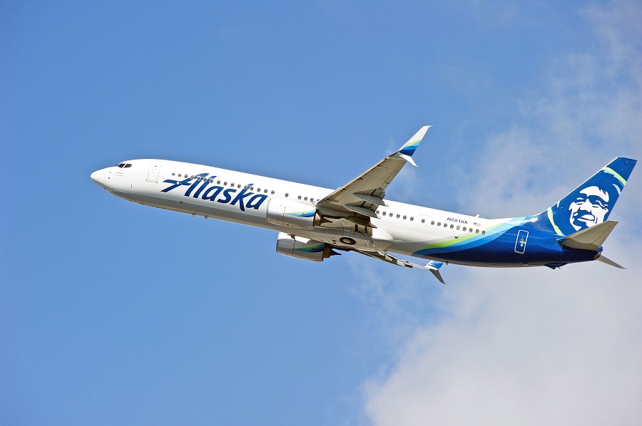 Alaska Airlines plan flying in sky with clouds