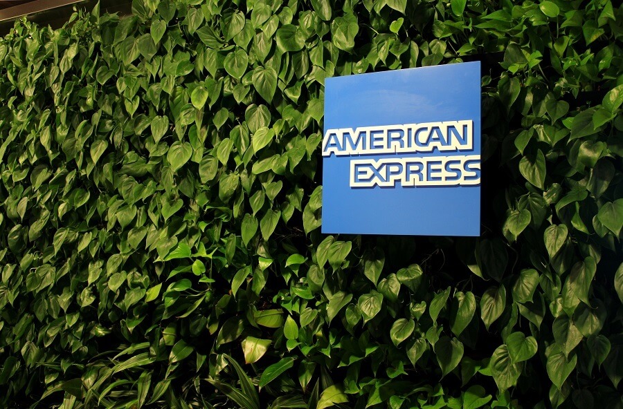 American Express logo on a green leafed wall