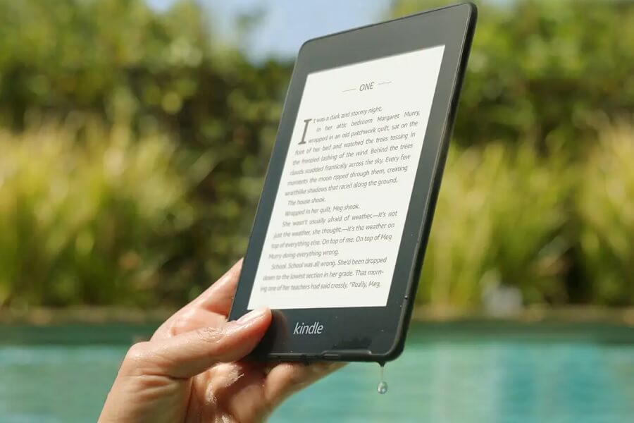 Black Kindle held by a woman's hand around water