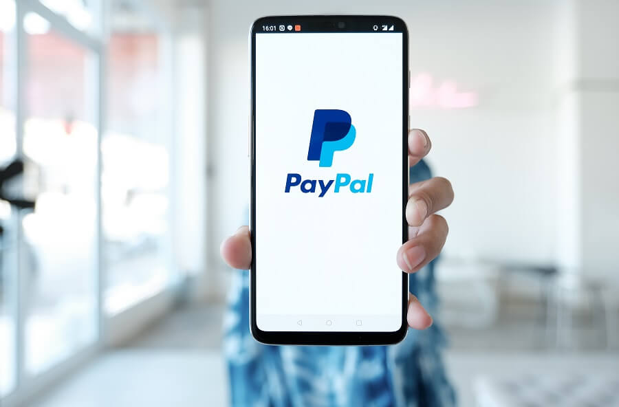 Person holding phone with PayPal logo on it